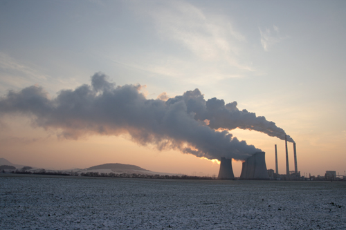 Photo of a power plant with steam/smoke coming out of its towers.