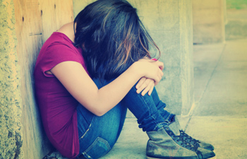 Young girl with her back against a wall sitting