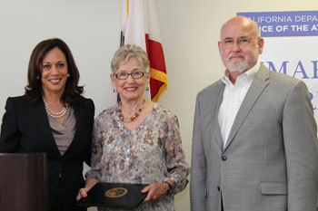AG Harris presents Suzy McCausland and Tom Gammon with a Smart on Crime Award.